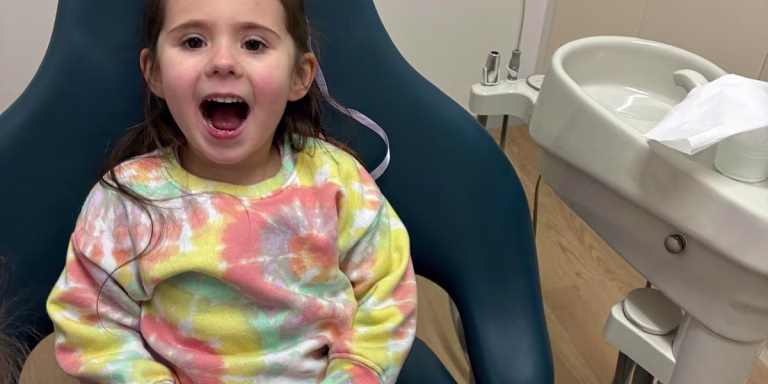 Smiling young child showing healthy teeth at a stress-free dental visit